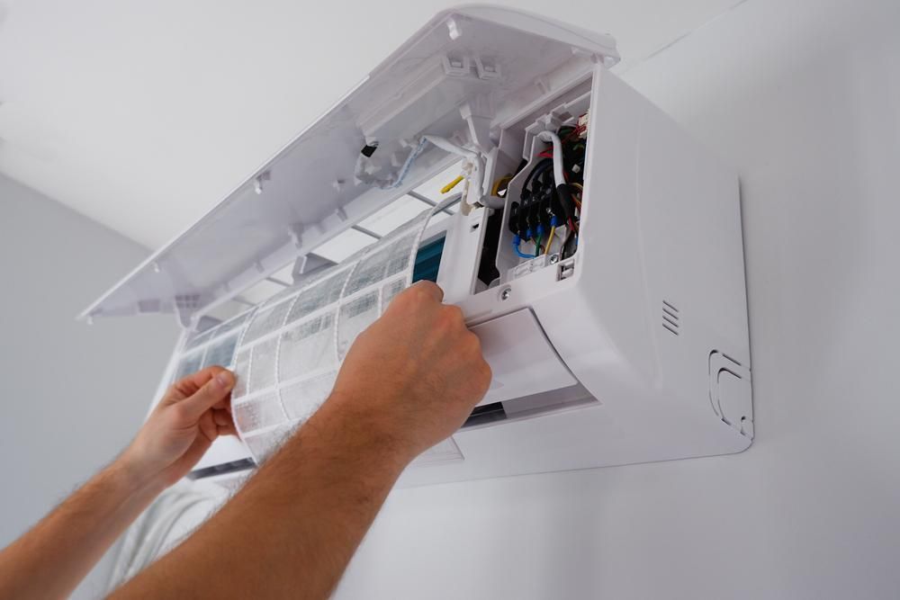 A Person is Cleaning the Filter of an Air Conditioner — Atmosphere Air Conditioning & Refrigeration In Nelson Bay, NSW