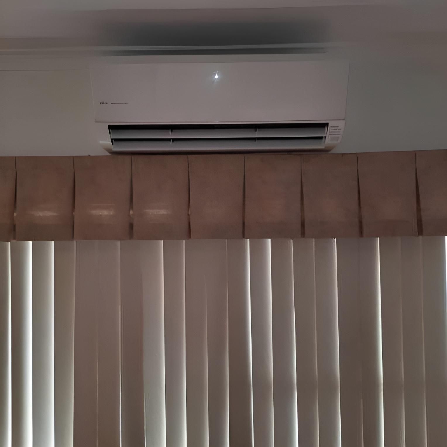 A White Air Conditioner Above a Window — Atmosphere Air Conditioning & Refrigeration In Taylors Beach, NSW