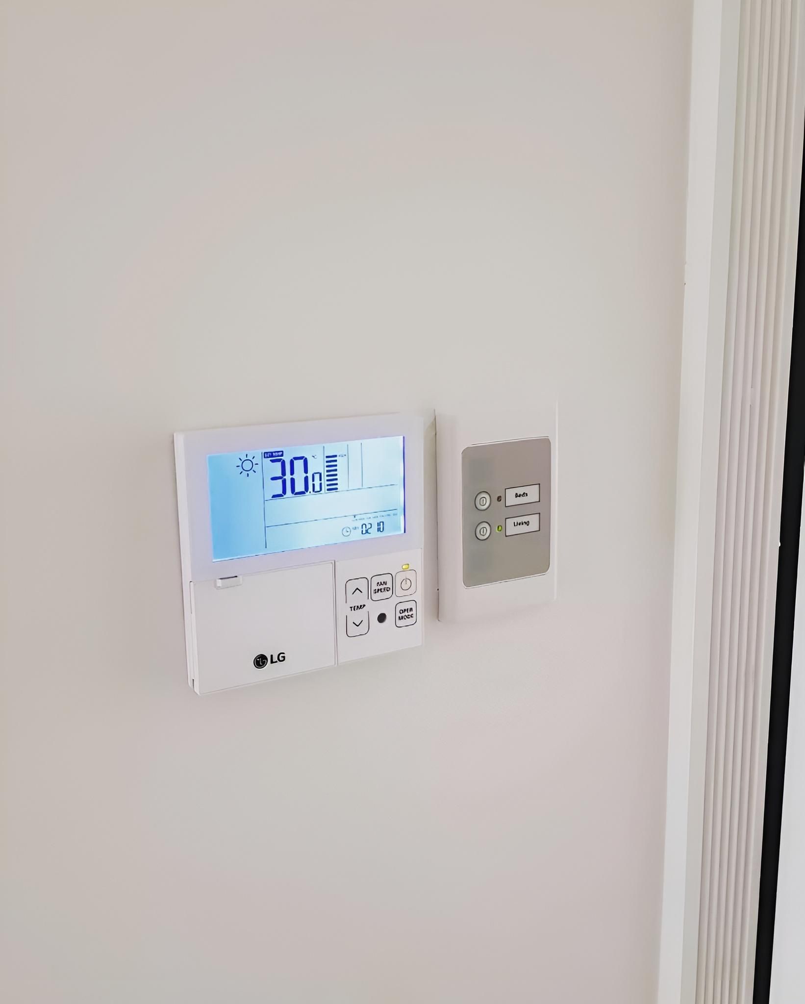 A White Thermostat is Hanging on a White Wall — Atmosphere Air Conditioning & Refrigeration In Anna Bay, NSW