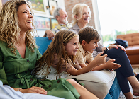 People sitting together on a couch, smiling and using a smartphone in a bright living room