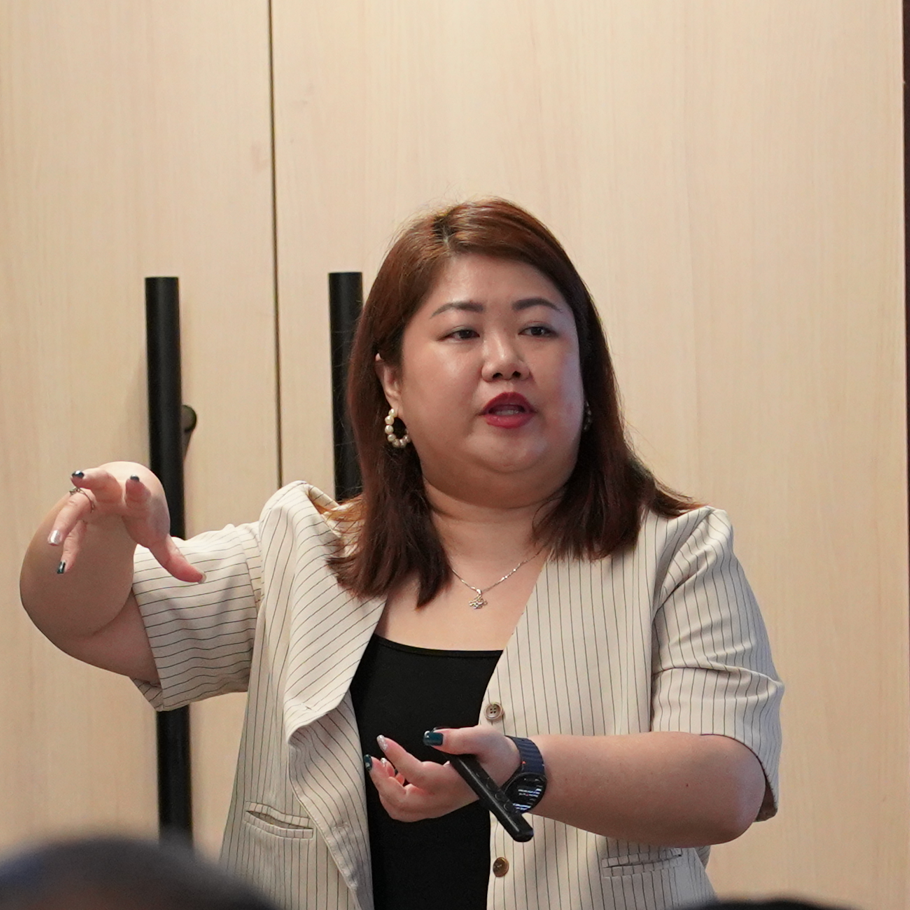 A woman giving a presentation to a group of people in a classroom.