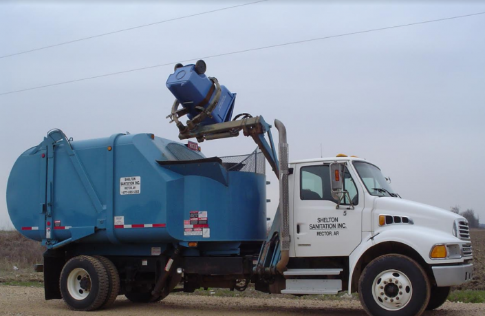 Blue garbage truck with an elevated worker dumping trash outdoors