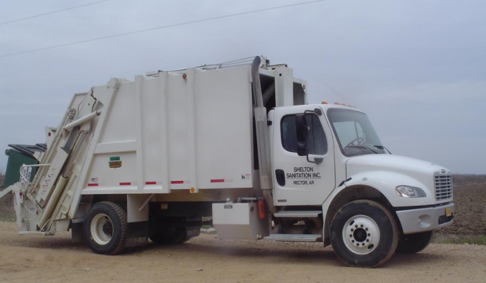 White garbage truck parked on a dirt lot under a cloudy sky, side view.