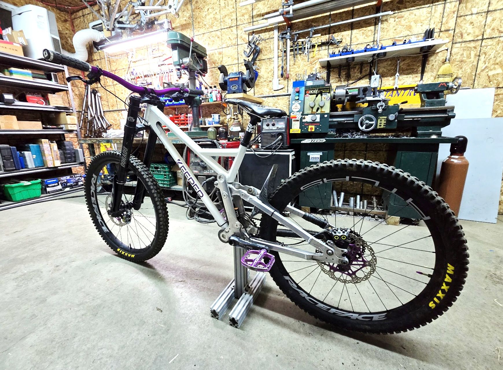 A silver mountain bike with purple accents, in a workshop setting.