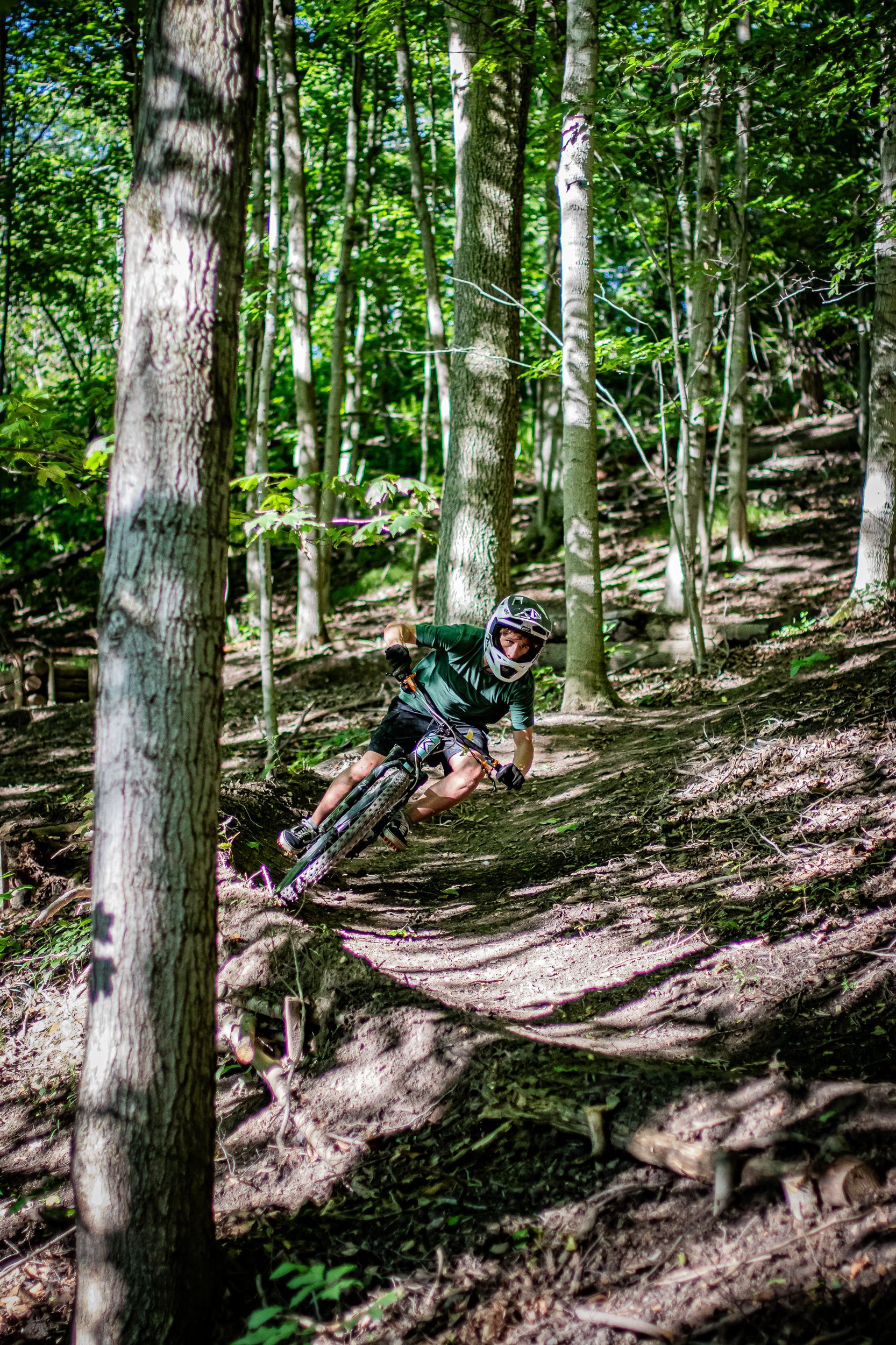 Person riding a purple mountain bike on a dirt trail in a forest.
