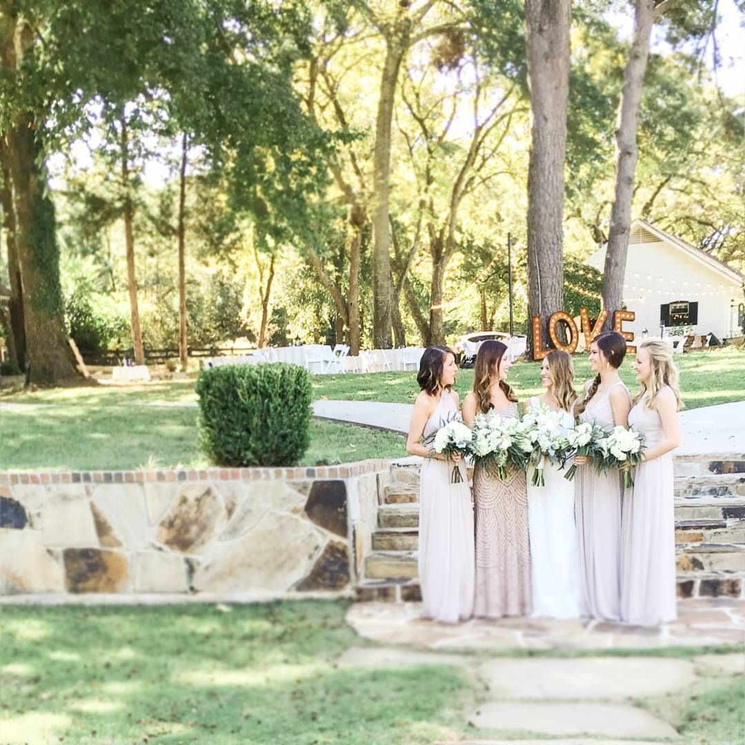 Bridesmaids with bouquets pose outdoors by a stone wall; 