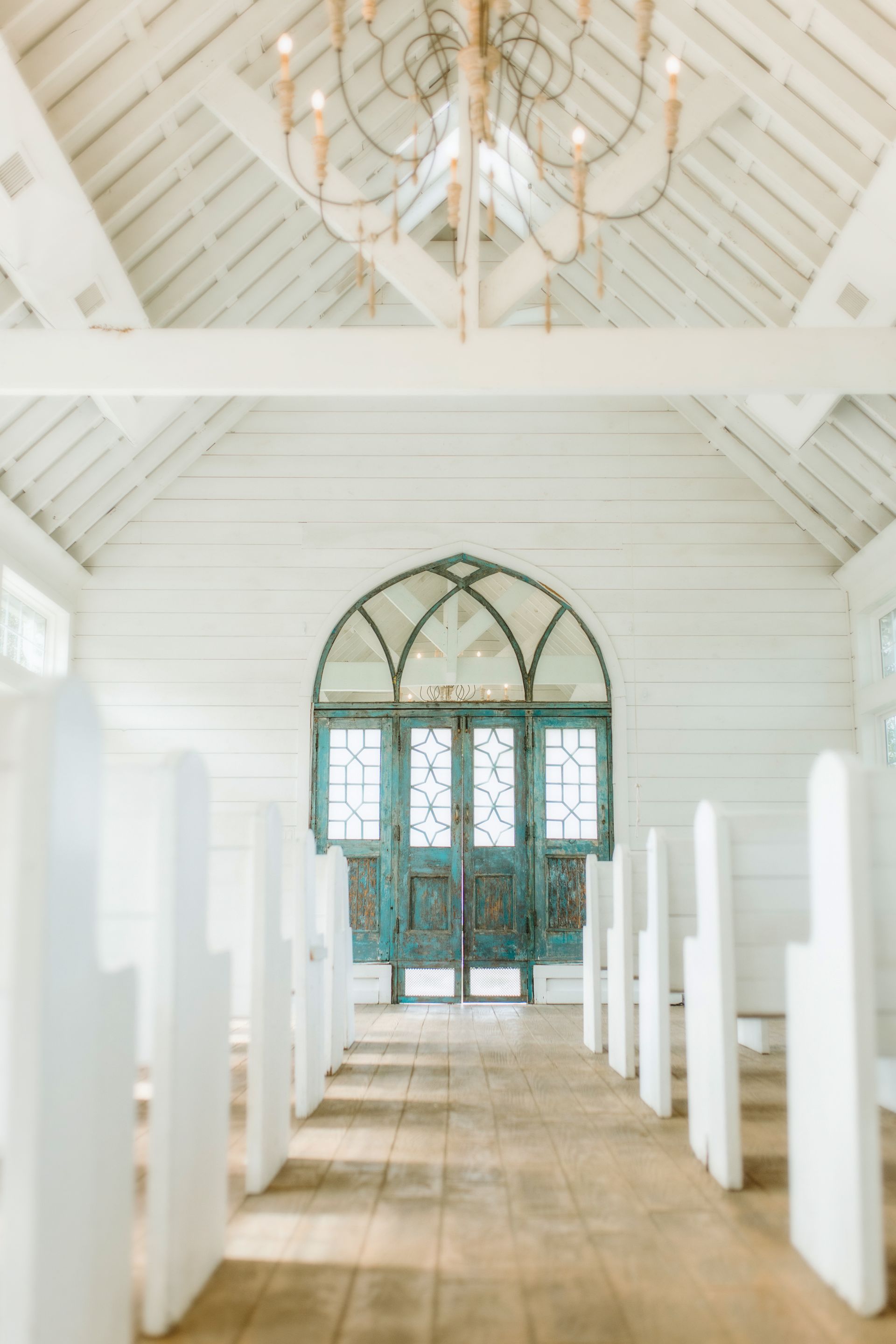 White chapel interior with turquoise doors and wooden pews.