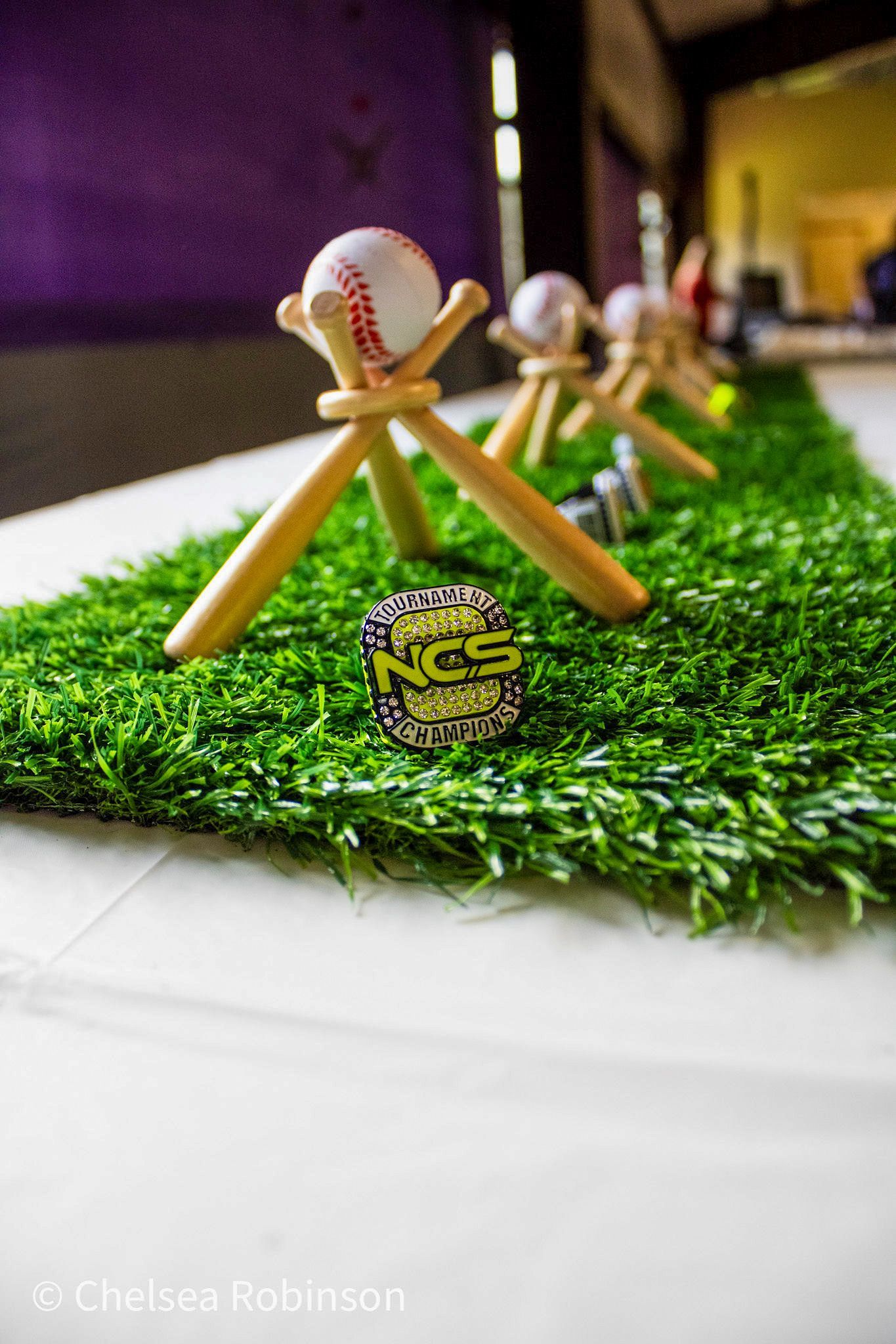 Baseball display with balls on wooden stands, green turf, and championship ring.