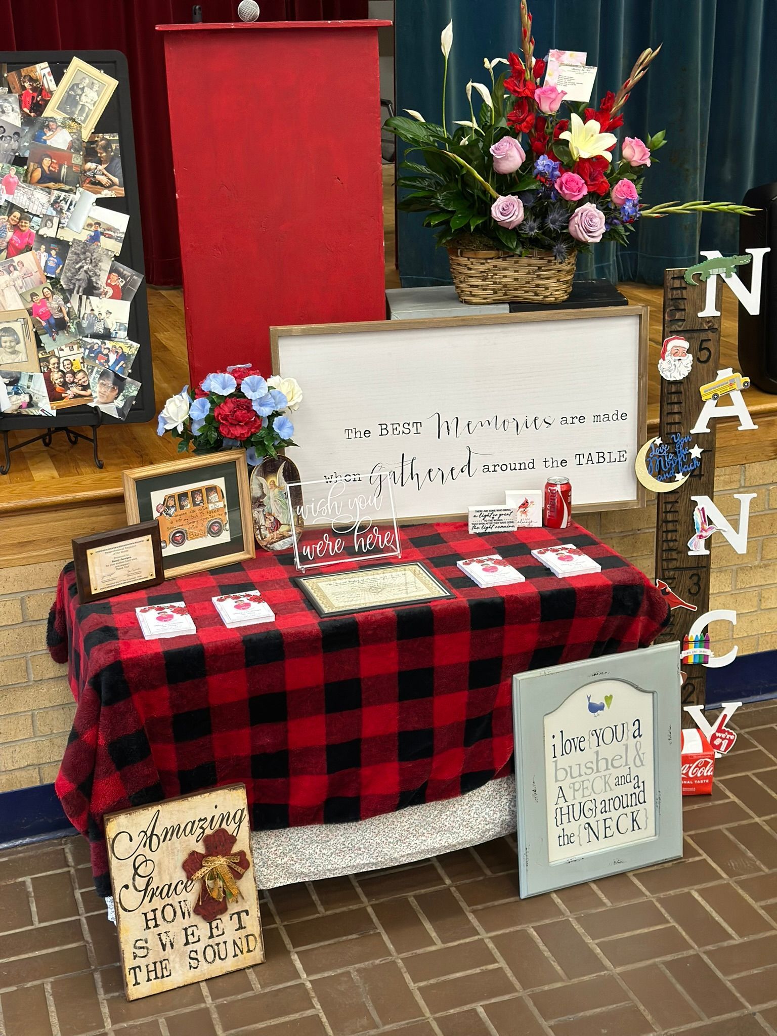 Display table with red and black plaid cloth, decorations, and flowers. 