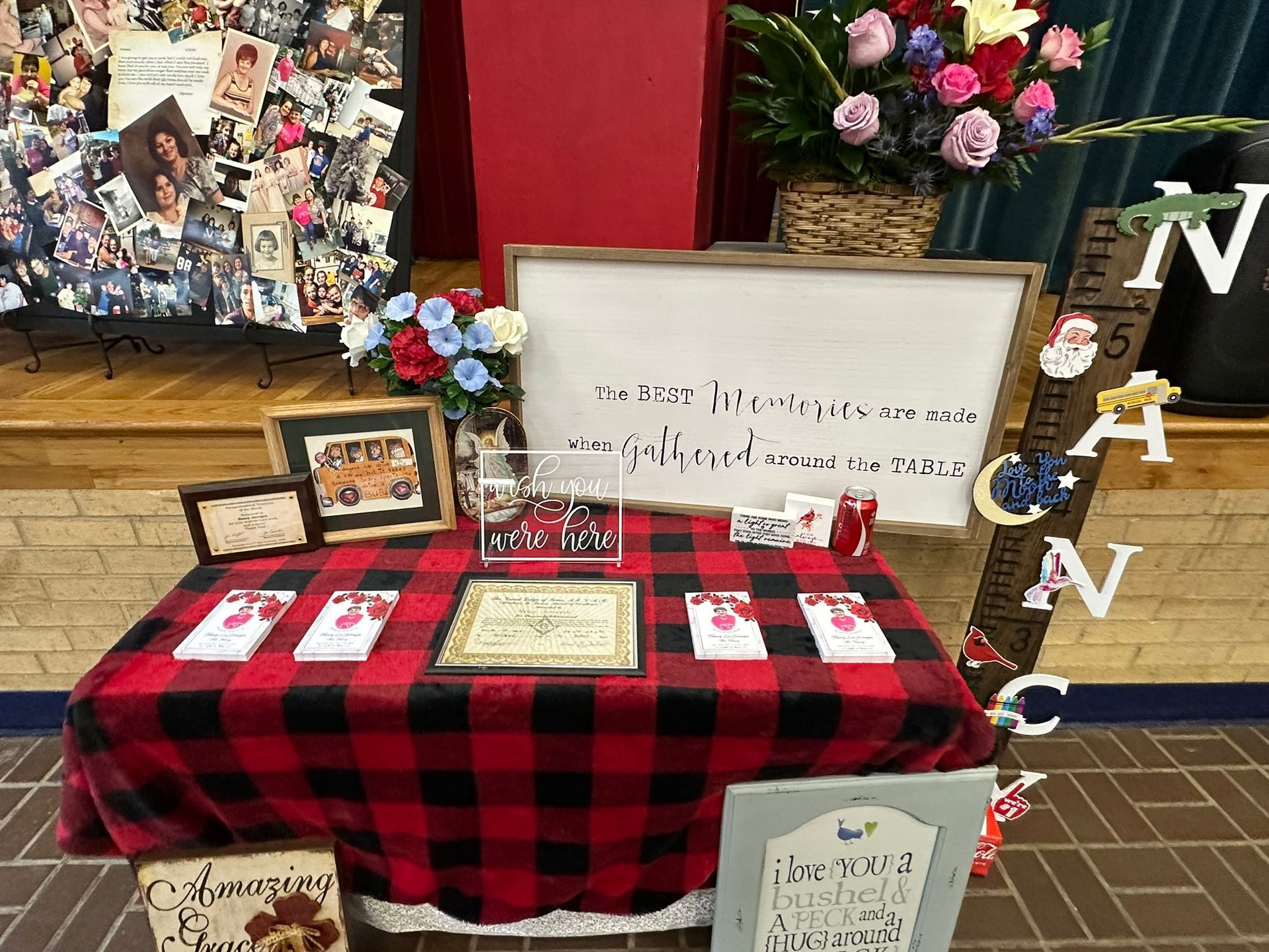 Table with red plaid tablecloth, decorations, flowers, and cards, presumably for an event.