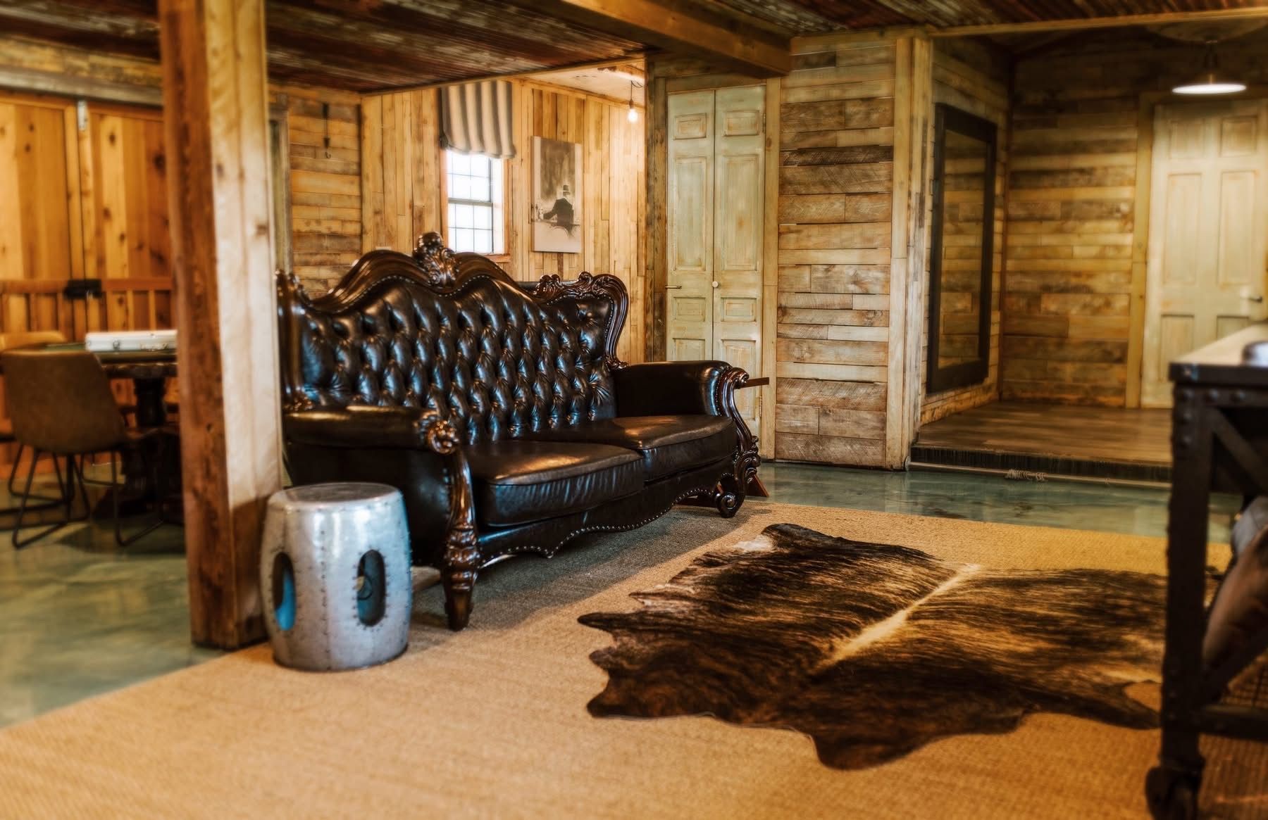 Living room with a tufted leather sofa, rug, and rustic wooden walls.