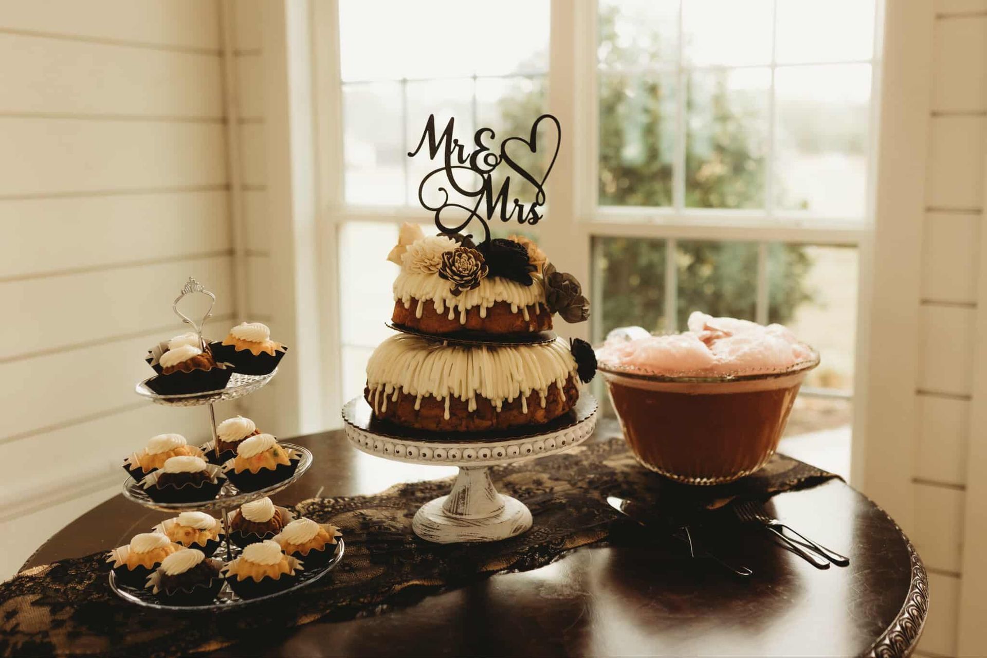 Wedding cake and cupcakes on a table with a 