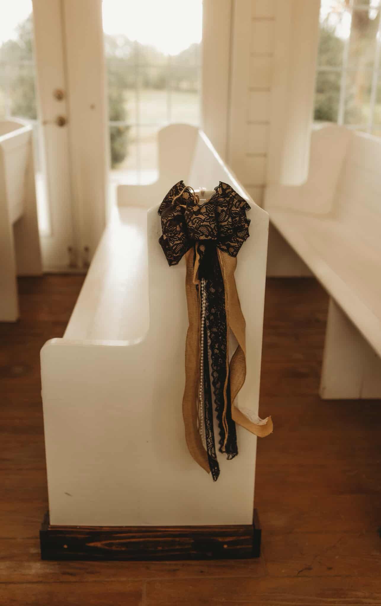 White church pew with a decorative bow.