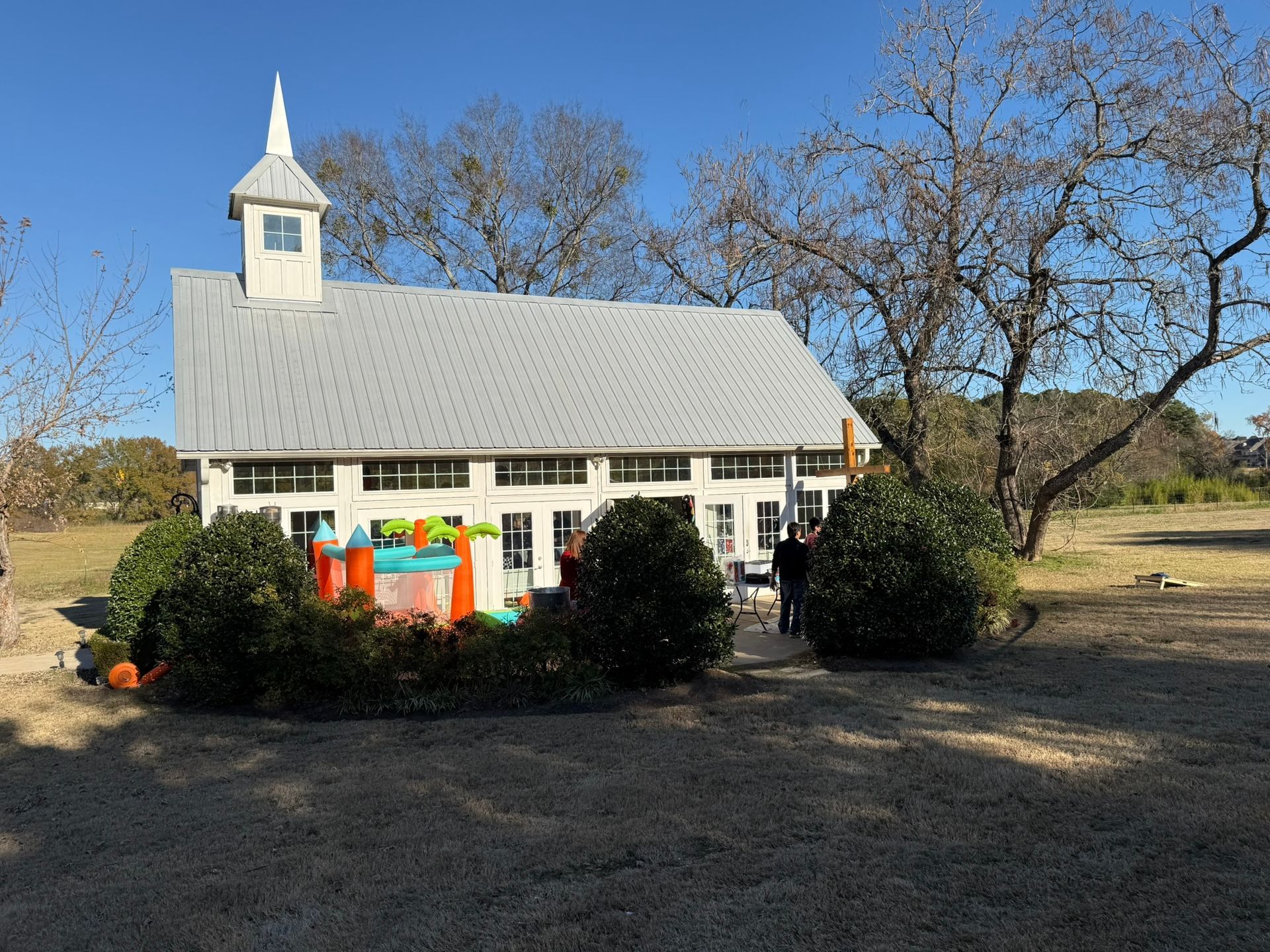 White chapel-like building with a small steeple. A bouncy castle is in front, and bushes surround the building.