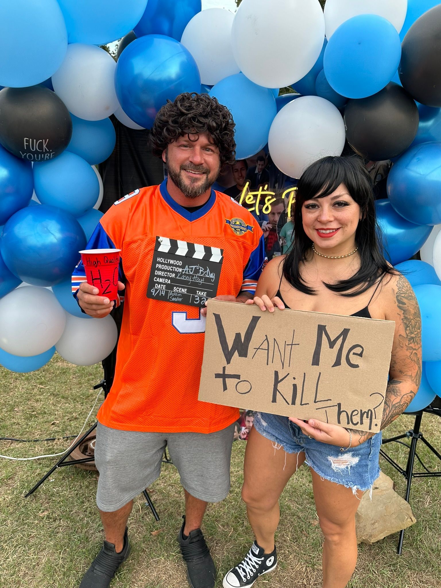 Two people posing with a sign. The woman holds a sign reading 