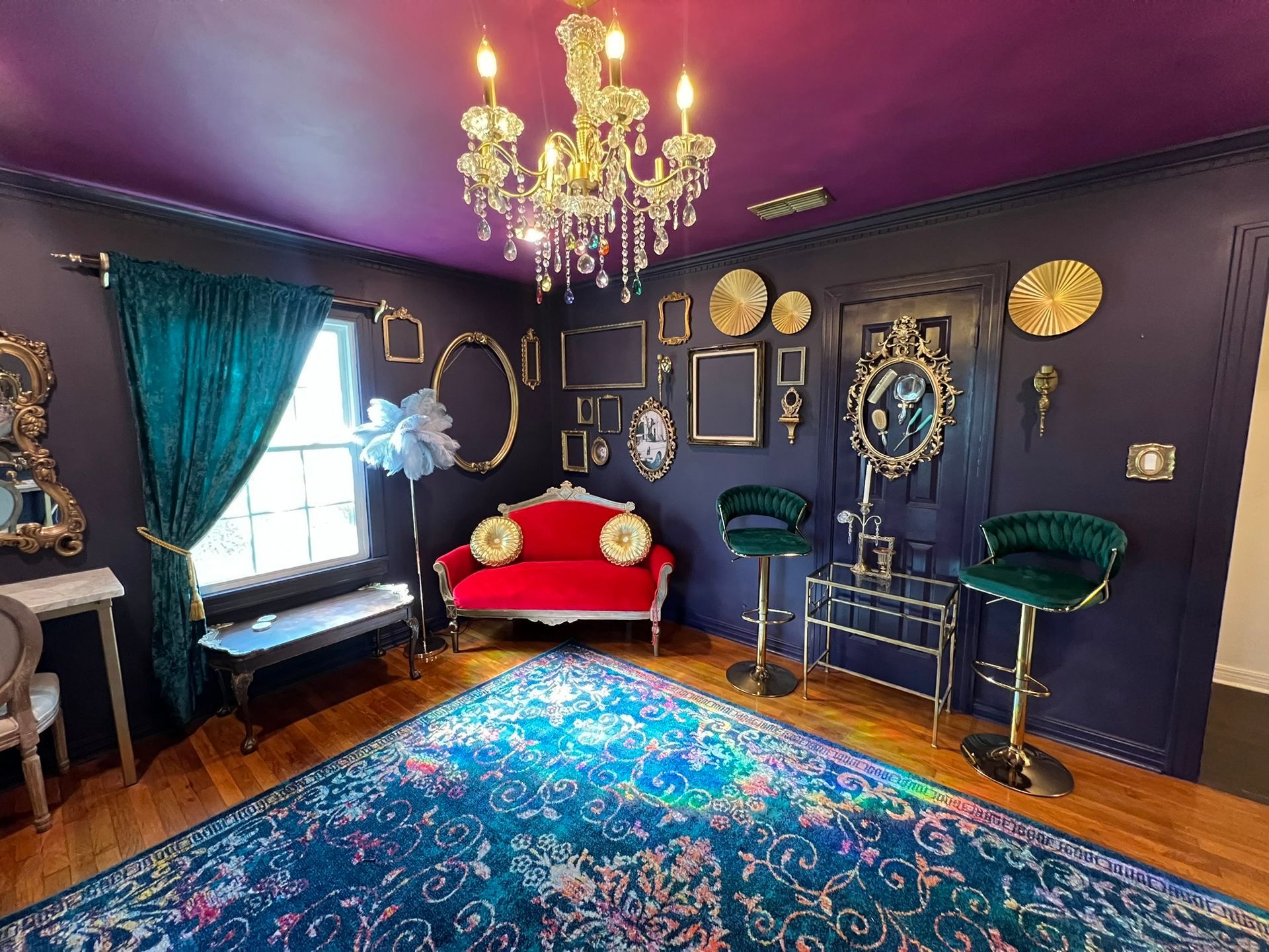 Lavish room with blue walls, red sofa, gold accents, and a jewel-toned rug.