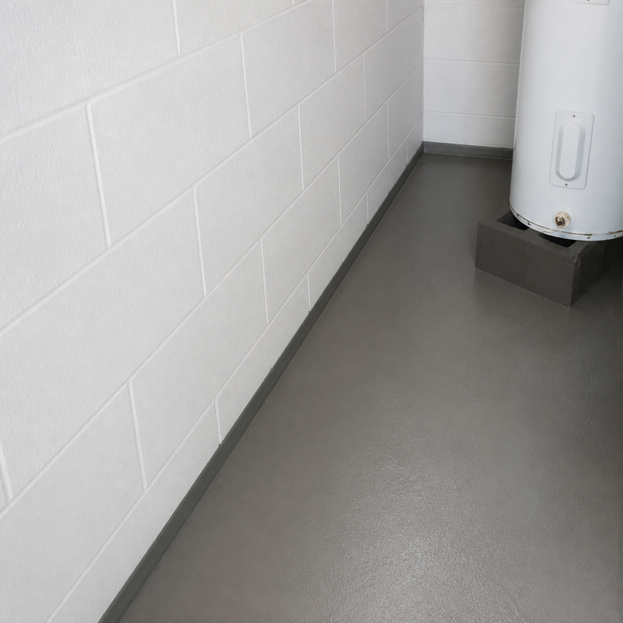 Empty utility room with a white wall, gray floor, and a water heater in the corner