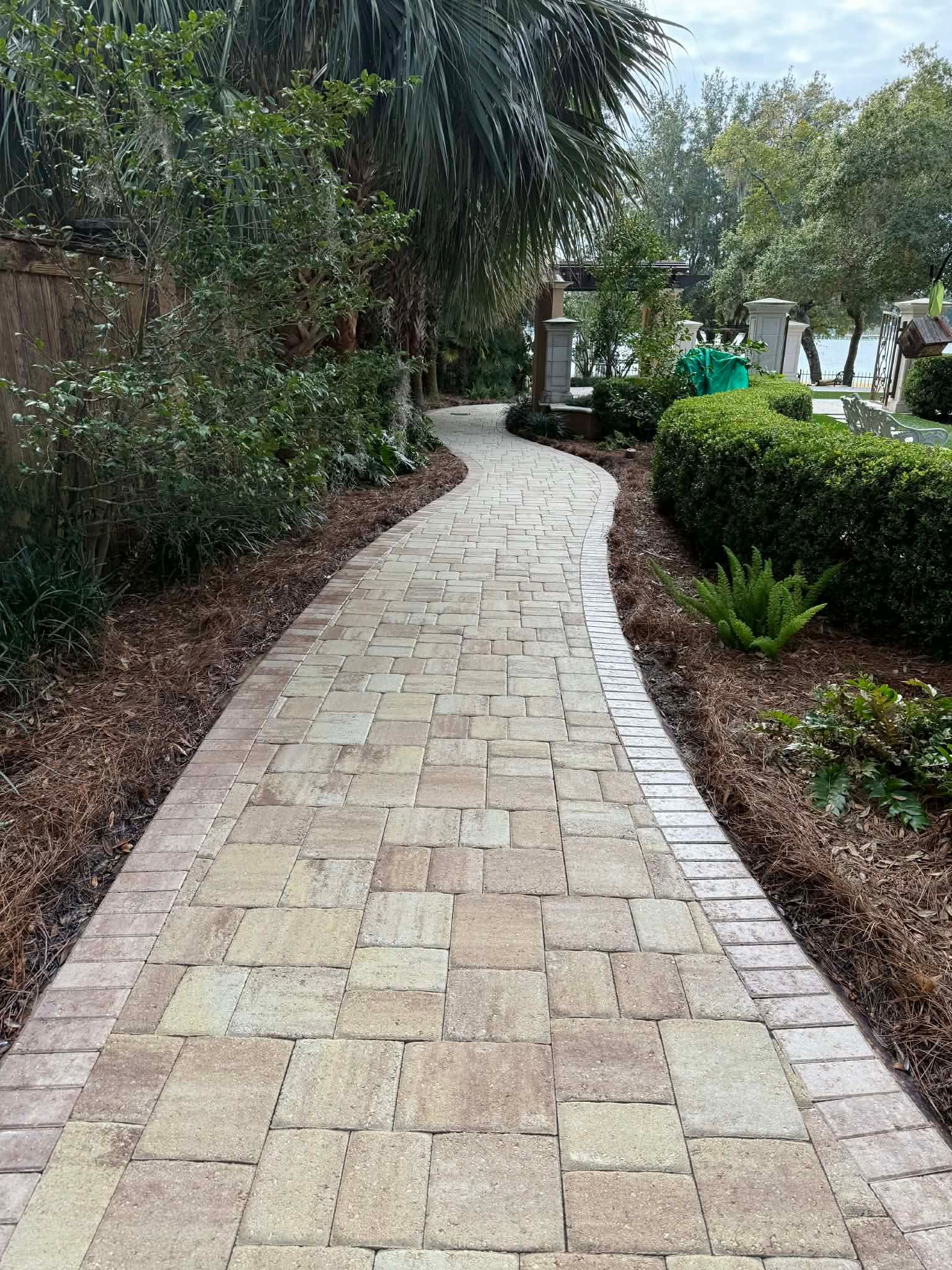 Clean matte-sealed paver walkway winding through landscaped waterfront grounds