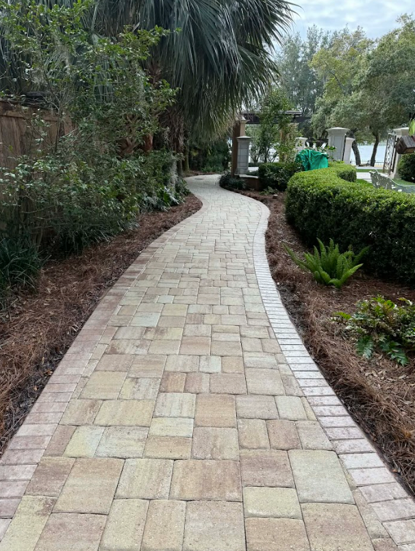 Curved stone walkway bordered by hedges and tropical plants in a landscaped garden