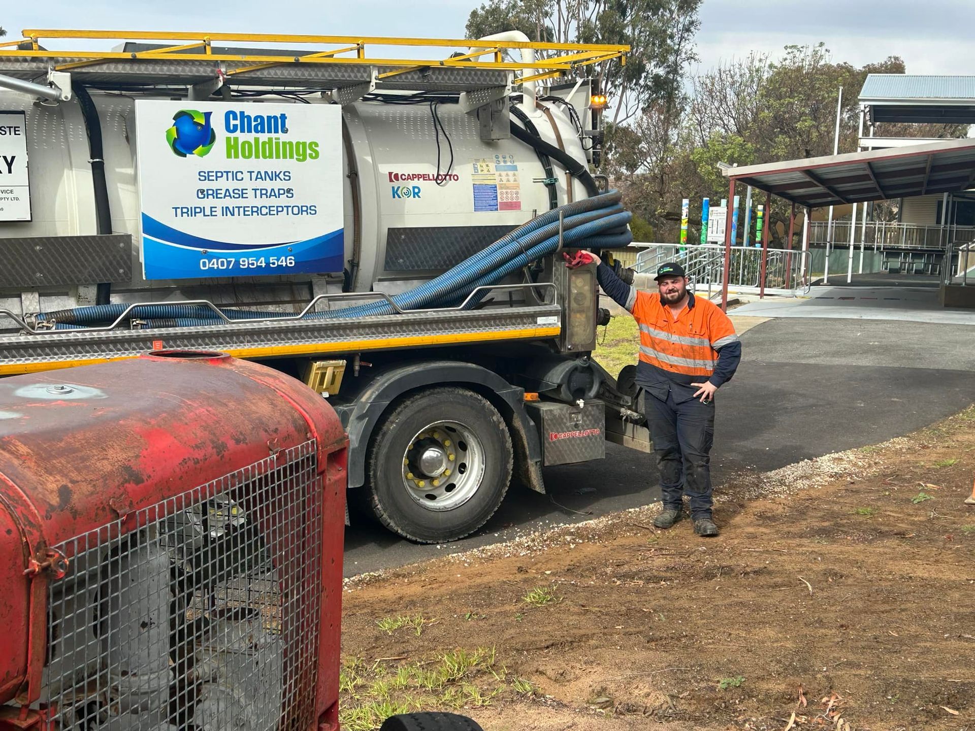 A man is standing in front of a vacuum truck.