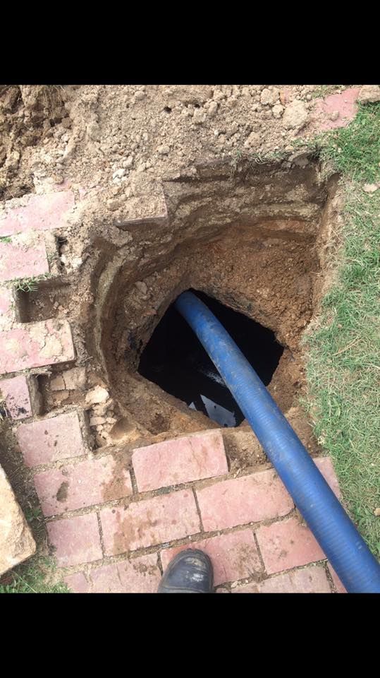 A blue pipe is coming out of a hole in the ground.