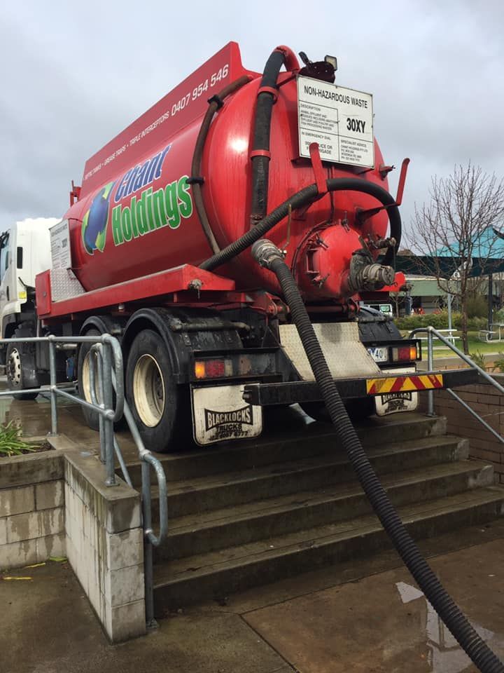 A red vacuum truck is parked on a set of stairs
