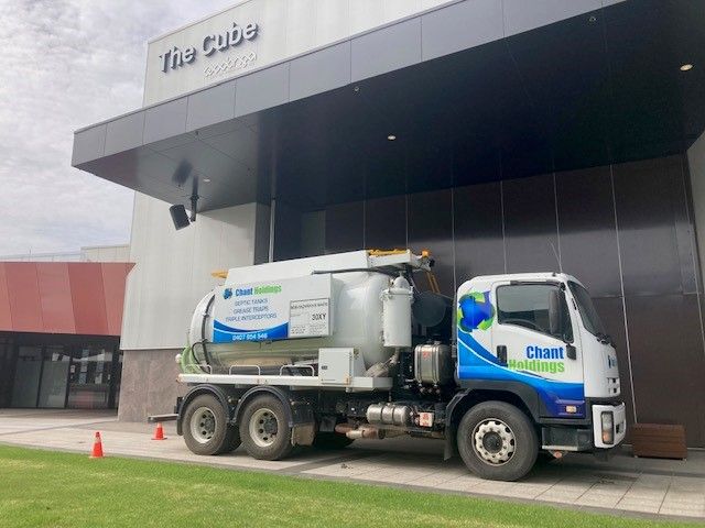 A vacuum truck is parked in front of a building.
