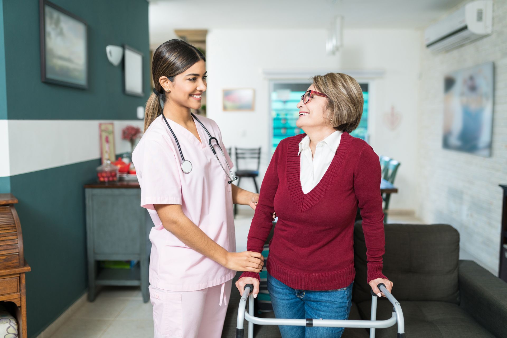 A confident caregiver supporting an elderly woman in her walker at home.