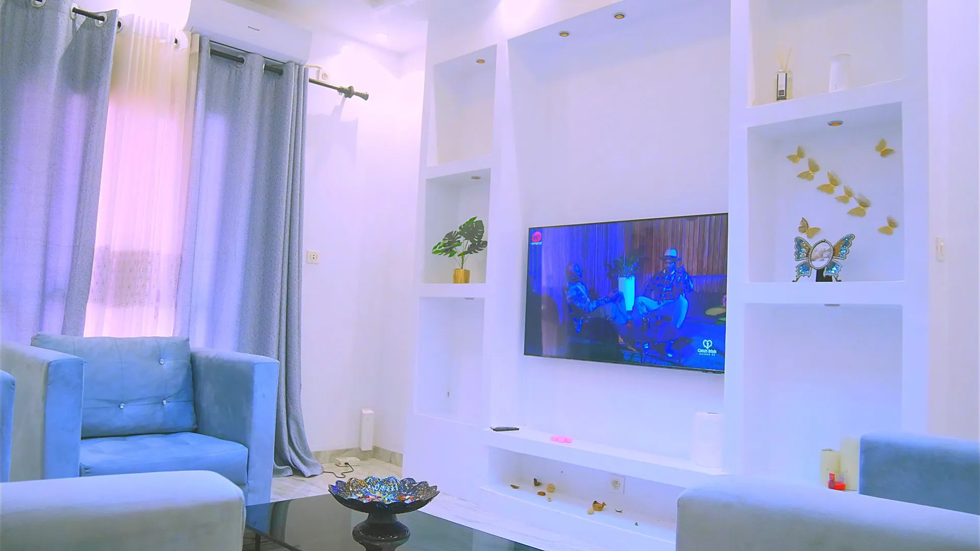 Un salon avec un canapé, un fauteuil et une télévision.