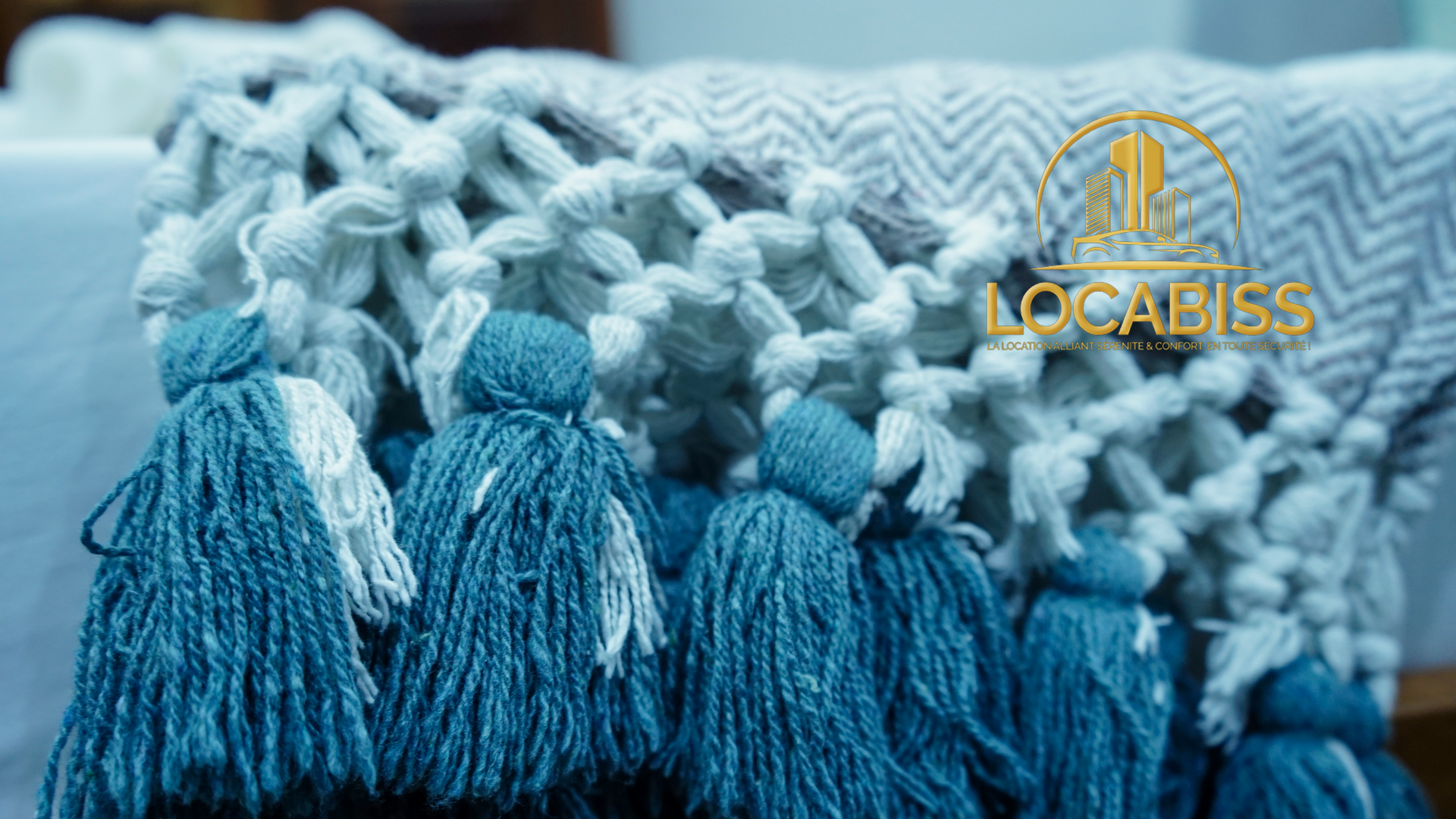 Un gros plan d'une couverture bleue et blanche avec des pompons.