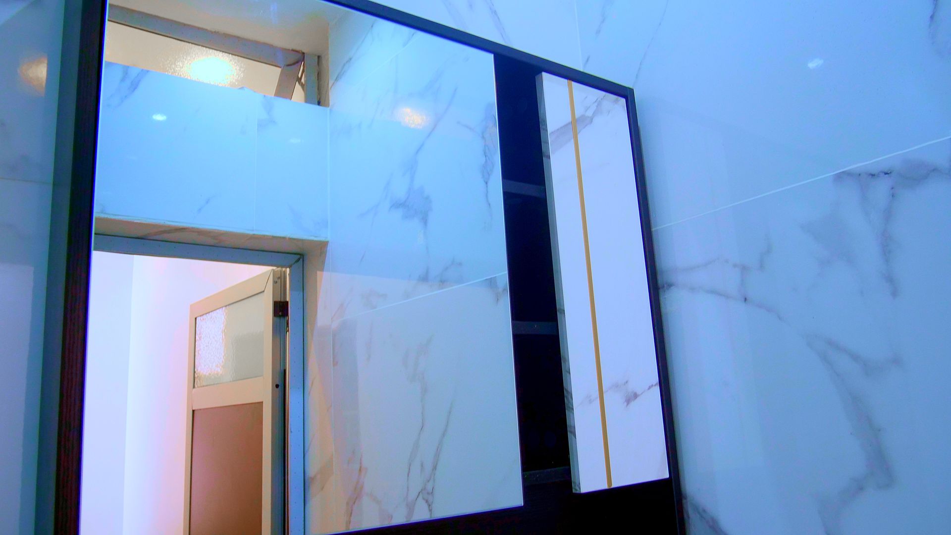 Une salle de bain avec un miroir au mur et une porte.