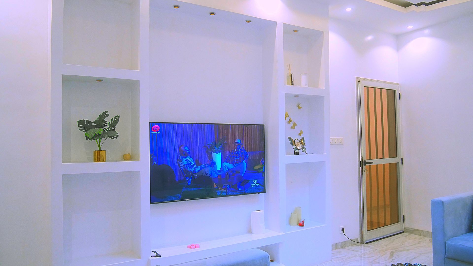 Un salon avec une télévision à écran plat au mur.
