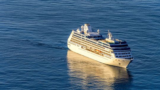 White cruise ship sailing on calm blue ocean under bright sunlight