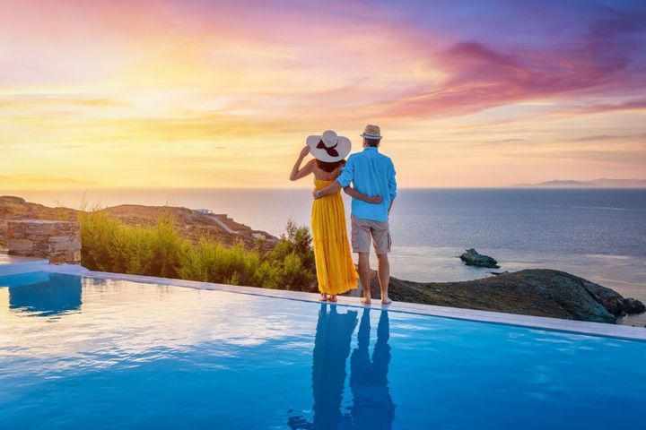Couple by an infinity pool at sunset, looking out over the ocean.