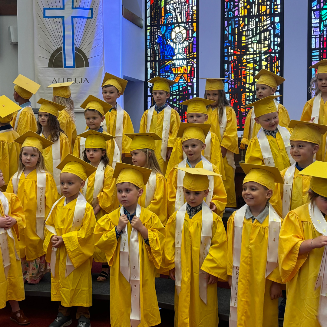 A group of children wearing yellow graduation gowns and caps