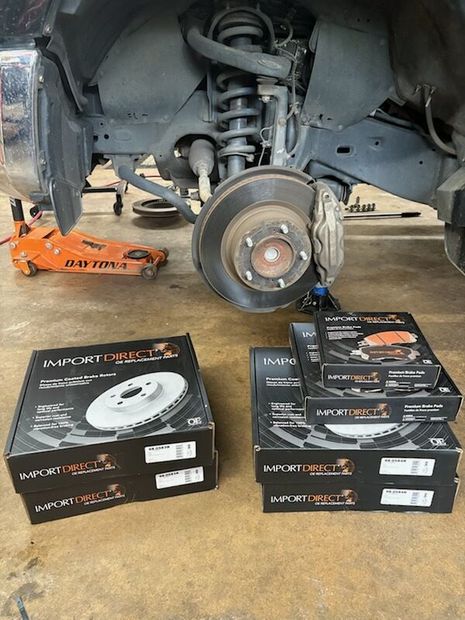 Car wheel removed in garage, showing brake and suspension with brake parts boxes in the foreground