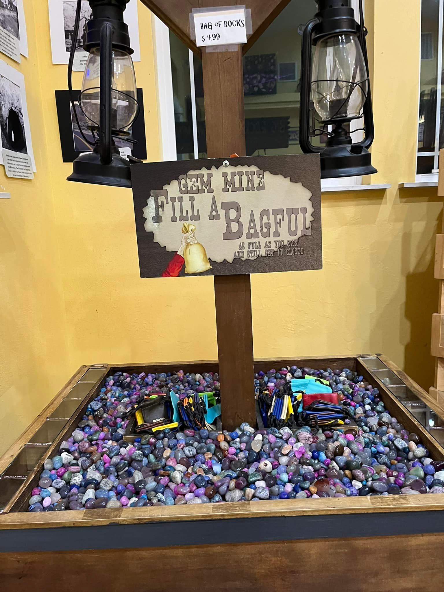 A wooden box filled with rocks and a sign that says `` fill a bagful ''.