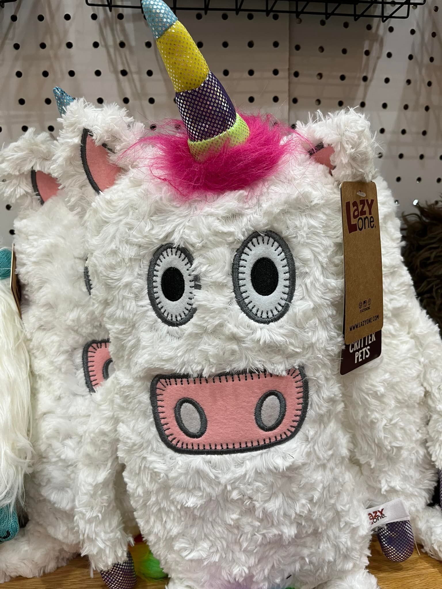 A stuffed unicorn with a pink horn is sitting on a table.