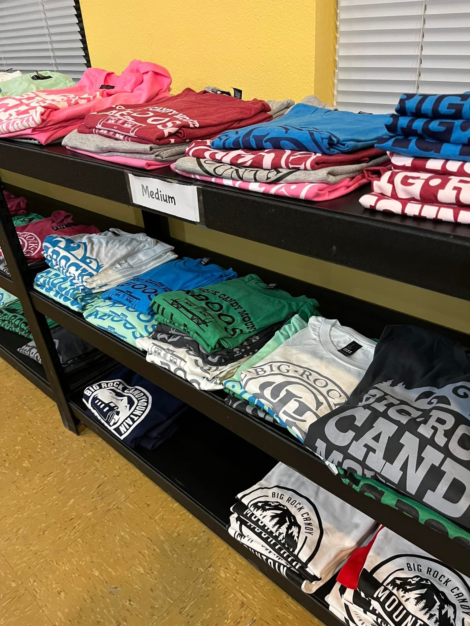 A shelf filled with lots of different colored t-shirts.