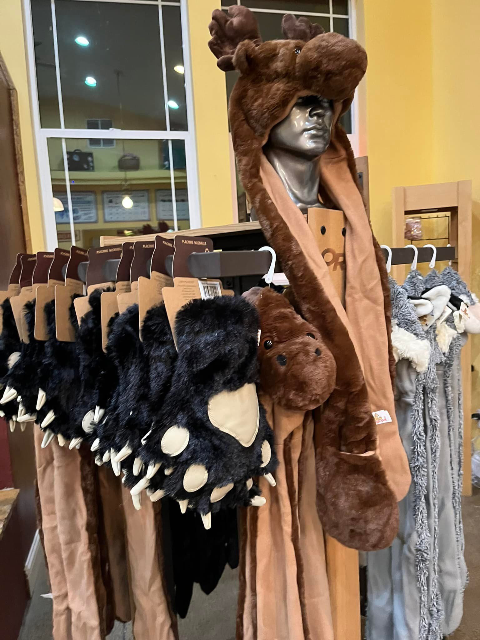 A mannequin is wearing a bear hat and scarf in a store.
