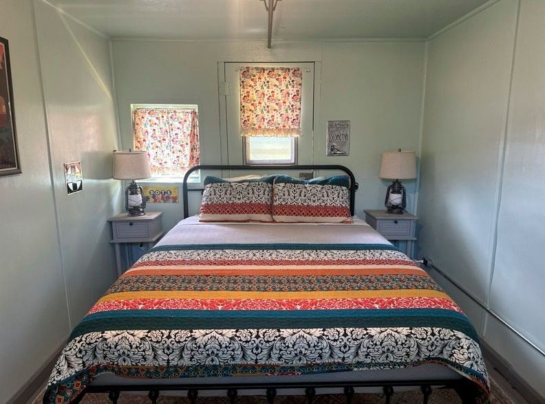 A bedroom with a bed , nightstands , lamps and a window.