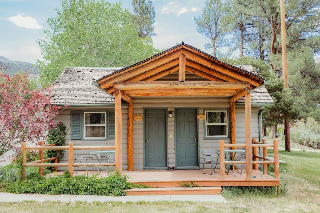 A small house with a porch and a fence in front of it.