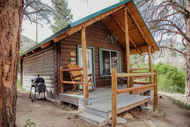 A small log cabin with a porch and rocking chairs.
