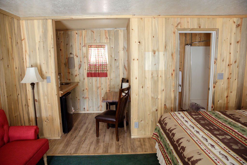 A bedroom with a bed , chair , table and lamp