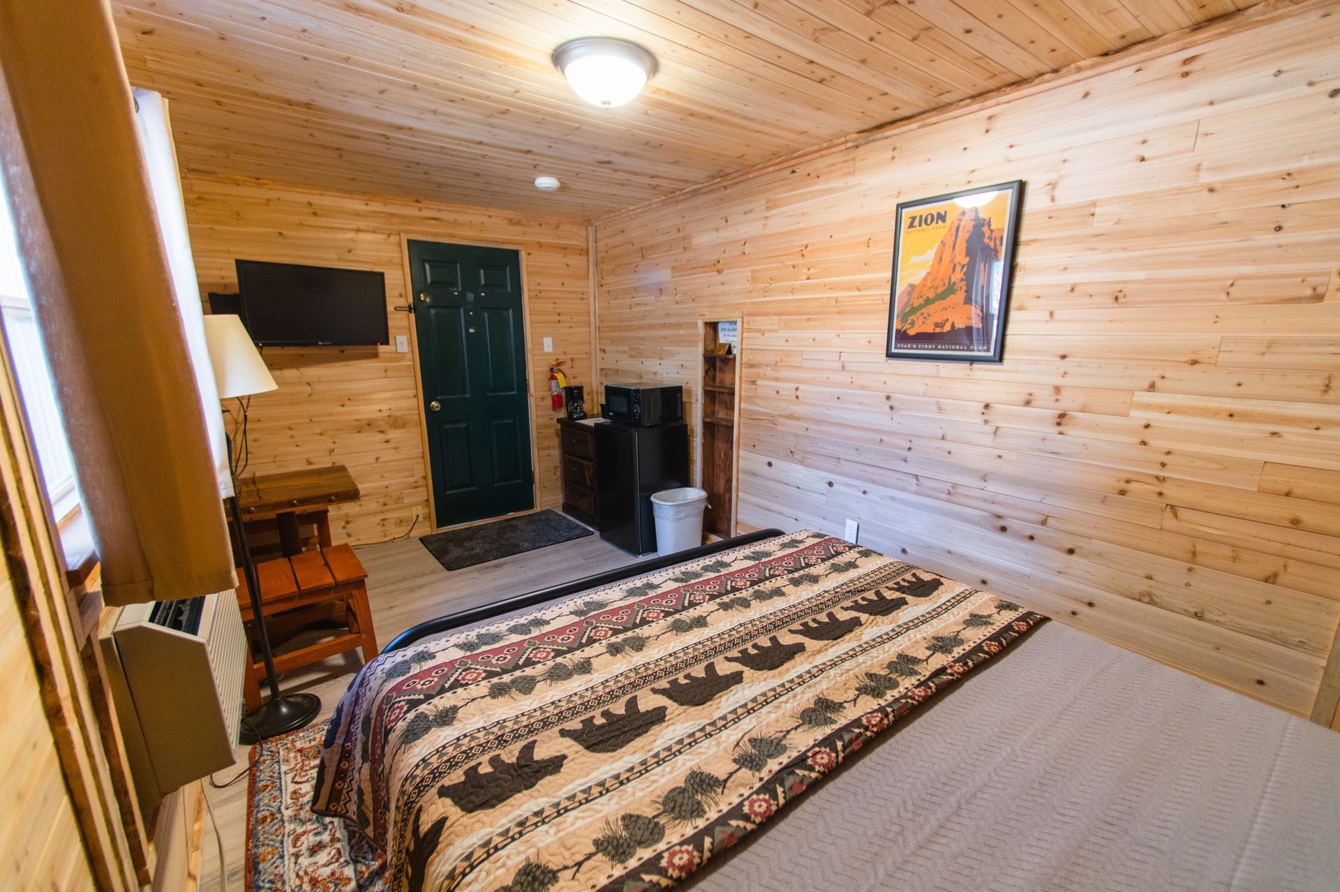 A bedroom in a log cabin with a king size bed and a television.