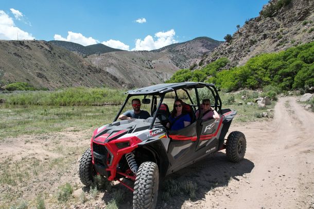 A group of people are sitting in a atv on a dirt road.