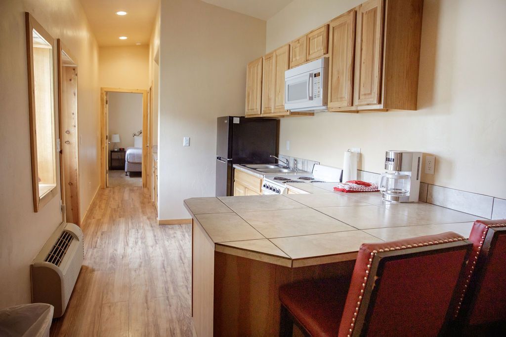 A hotel room with a kitchen and a hallway