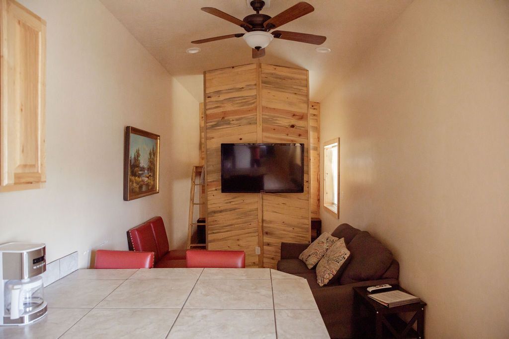 A living room with a ceiling fan and a flat screen tv.