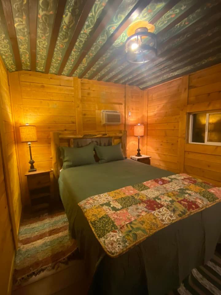 A bedroom with a bed , two lamps , and a window.