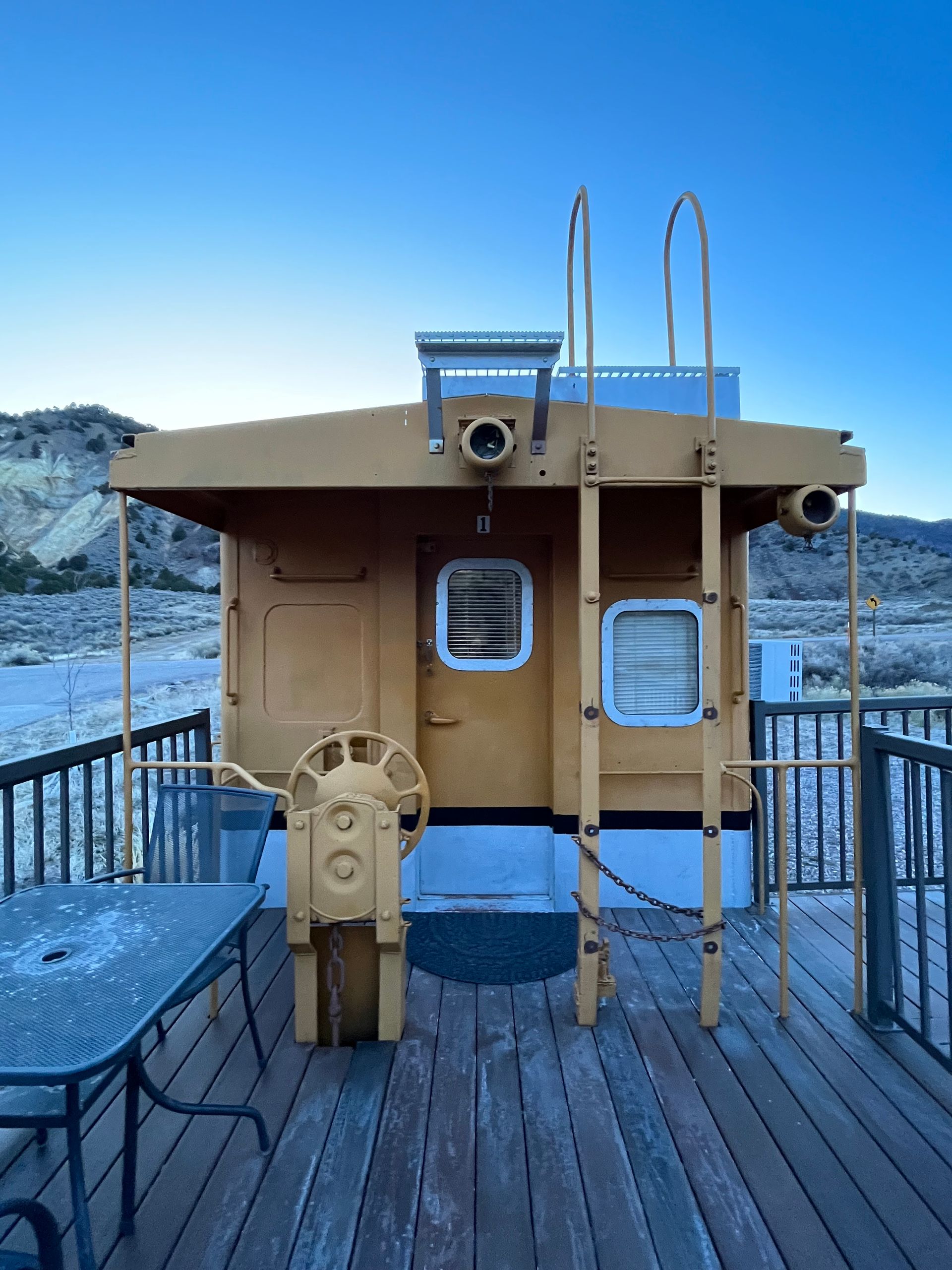 A wooden deck with a table and chairs and a boat on it